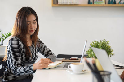 Young woman using mobile phone on table