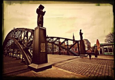 Man standing on footpath in city against sky