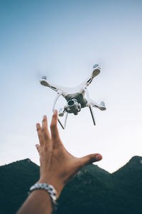 Midsection of person holding airplane flying against sky