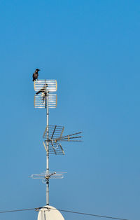 Low angle view of communications tower against clear blue sky