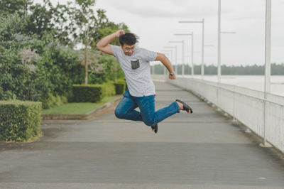 Rear view of man jumping on footpath