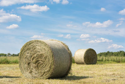 Hay bales on field against sky