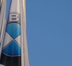 Low angle view of sign on pole against clear blue sky