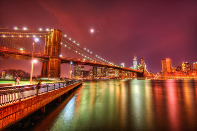 Illuminated bridge over river at night