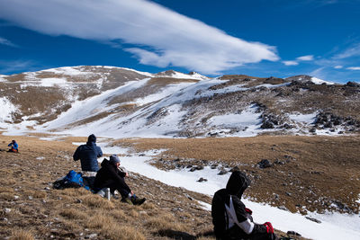 Rear view of people on snowcapped mountain against sky