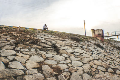 Man walking on rocks against sky