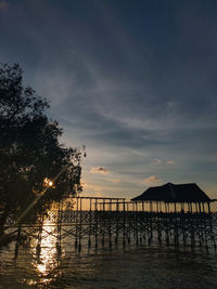 Silhouette trees by sea against sky during sunset