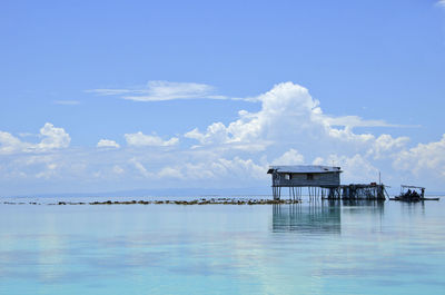 Stilt house over sea against sky