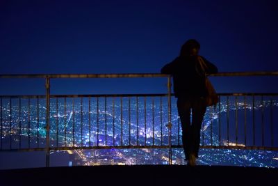 Man standing in illuminated city against clear blue sky