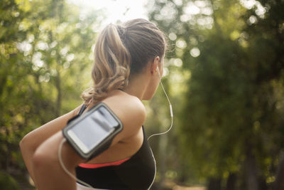Young woman looking away while sitting on tree