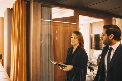 Male and female lawyers discussing while walking in office corridor