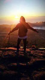 Rear view of man standing on mountain during sunset