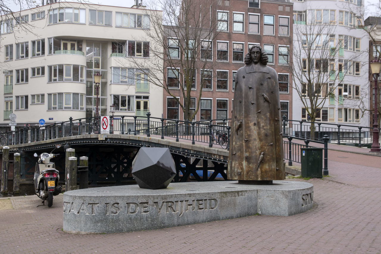 STATUE BY STREET IN CITY AGAINST BUILDINGS