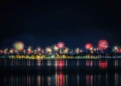 Illuminated firework display over river at night