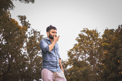 Side view of man standing against trees