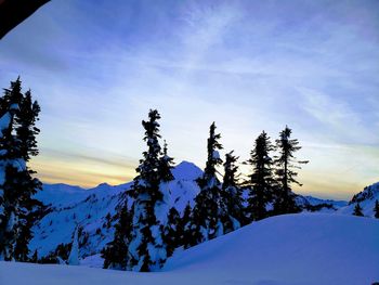 Scenic view of snow covered mountains against sky at sunset