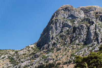 Low angle view of rock formation against clear blue sky