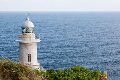 Lighthouse by sea against sky