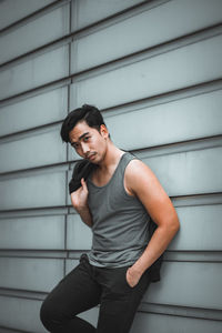 Side view of young man smiling against wall