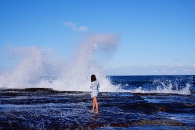 Rear view of man surfing in sea against sky