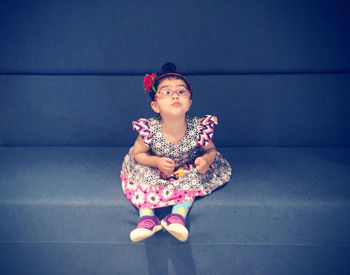 Girl looking away while sitting on sofa