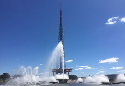Low angle view of water splashing against blue sky