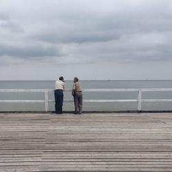 Pier on sea against cloudy sky