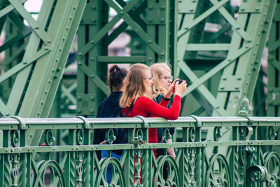 Woman with text on railing against bridge