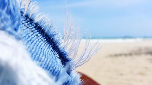 Close-up of sand on beach against blue sky