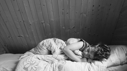 Boy sleeping on bed against wall at home