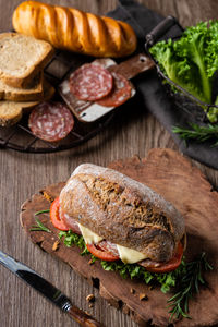 Hamburger made by whole wheat bread baked with ham, lettuce, tomato, pork sausage and cheese.