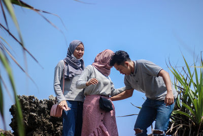 Low angle view of people standing by plants against sky