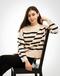 Young woman sitting on chair against white background