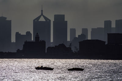 Silhouette buildings in city against sky