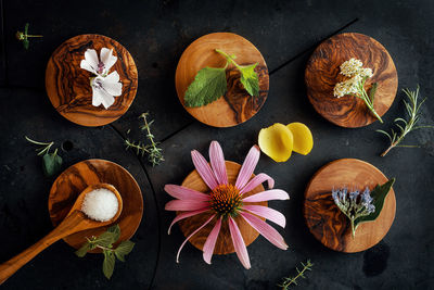 Various petals and salt on small wooden plates decorated with flowers