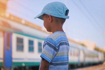 Boy looking at train against sky
