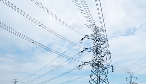 Low angle view of electricity pylon against blue sky