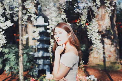 Portrait of young woman standing against plants in park