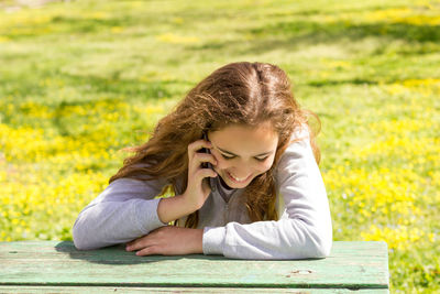 Side view of a smiling girl sitting on grass