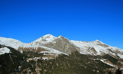 Scenic view of snowcapped mountains against clear blue sky