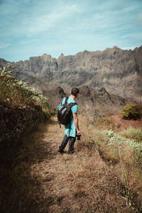 Rear view of friends walking on mountain against sky