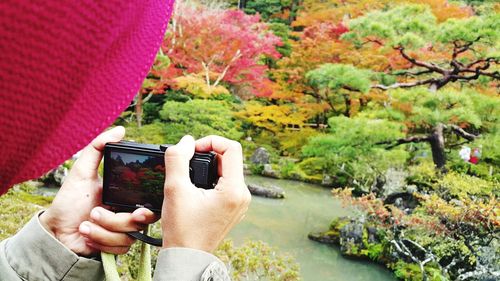 Midsection of man holding mobile phone against trees