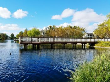 Footbridge over river against blue sky