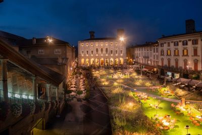 Illuminated street amidst buildings at night