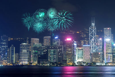 Firework display over illuminated buildings in city at night