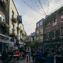 People on street amidst buildings in city against sky