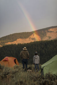 Rear view of couple camping on mountain against sky during sunset