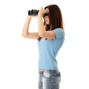 Woman holding camera while standing against white background