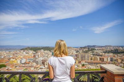 Rear view of woman looking at cityscape against sky