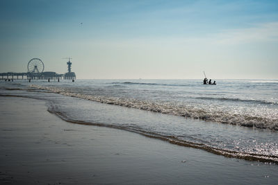 Scenic view of sea against sky with several people on a boat